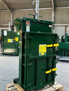PEL green cardboard and plastic baler closed with yellow handles in warehouse
